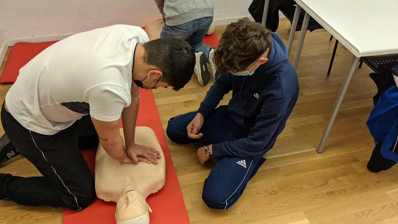 Trainees practising chest compressions on CPR manikins in a classroom